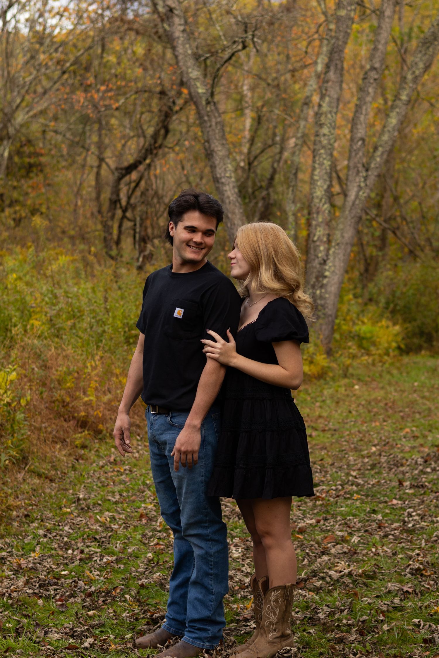 Couple sharing a lighthearted moment on a trail surrounded by autumn trees in Newark, Delaware.