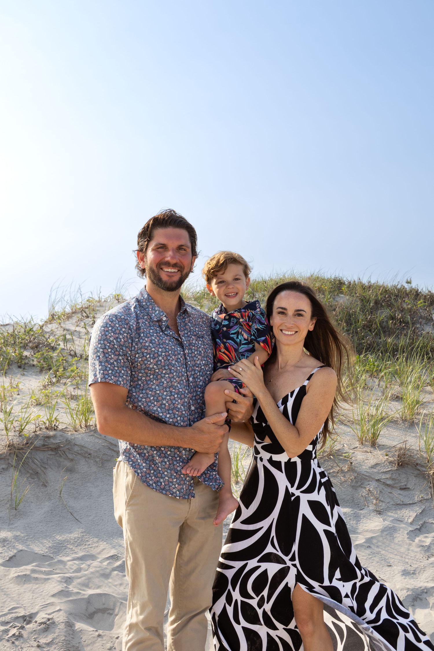 A family poses together on sandy beach dunes on a bright sunny day in Avalon, New Jersey.