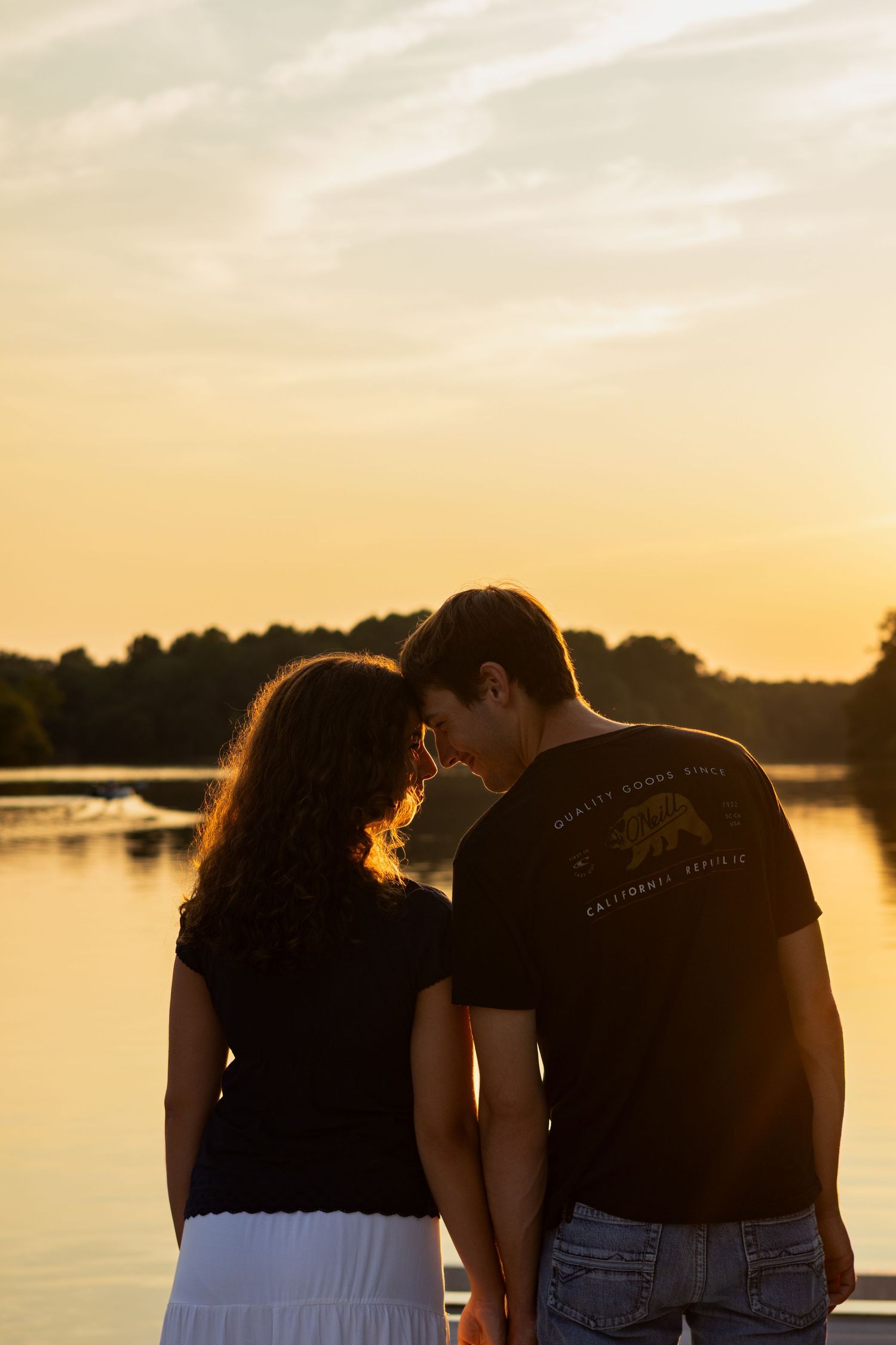 Silhouette of a couple standing by a lake during a golden sunset in Delaware.