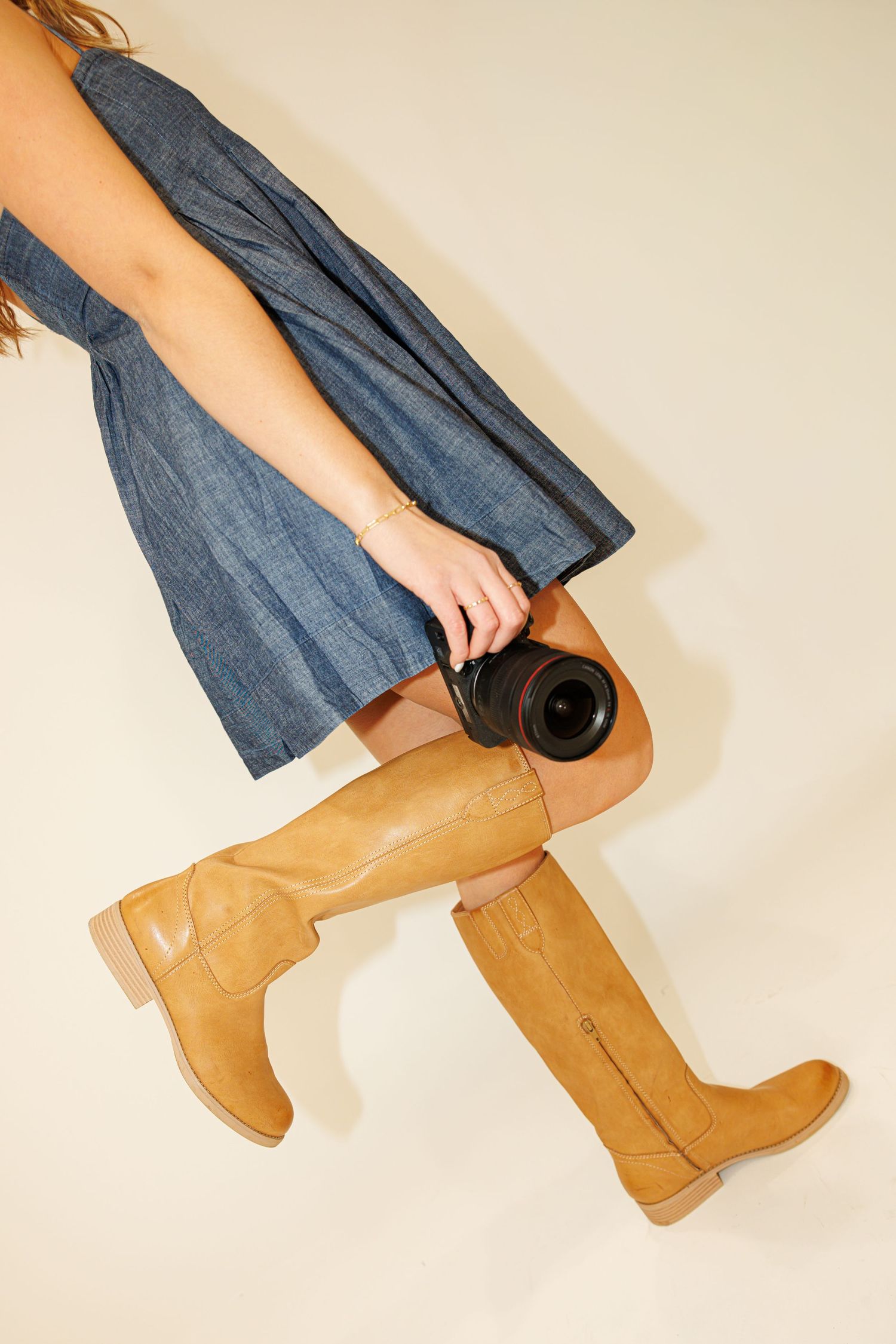 Tan leather boots and camera lens shown with denim dress in lifestyle product photography setup for Madison Adele Photography.