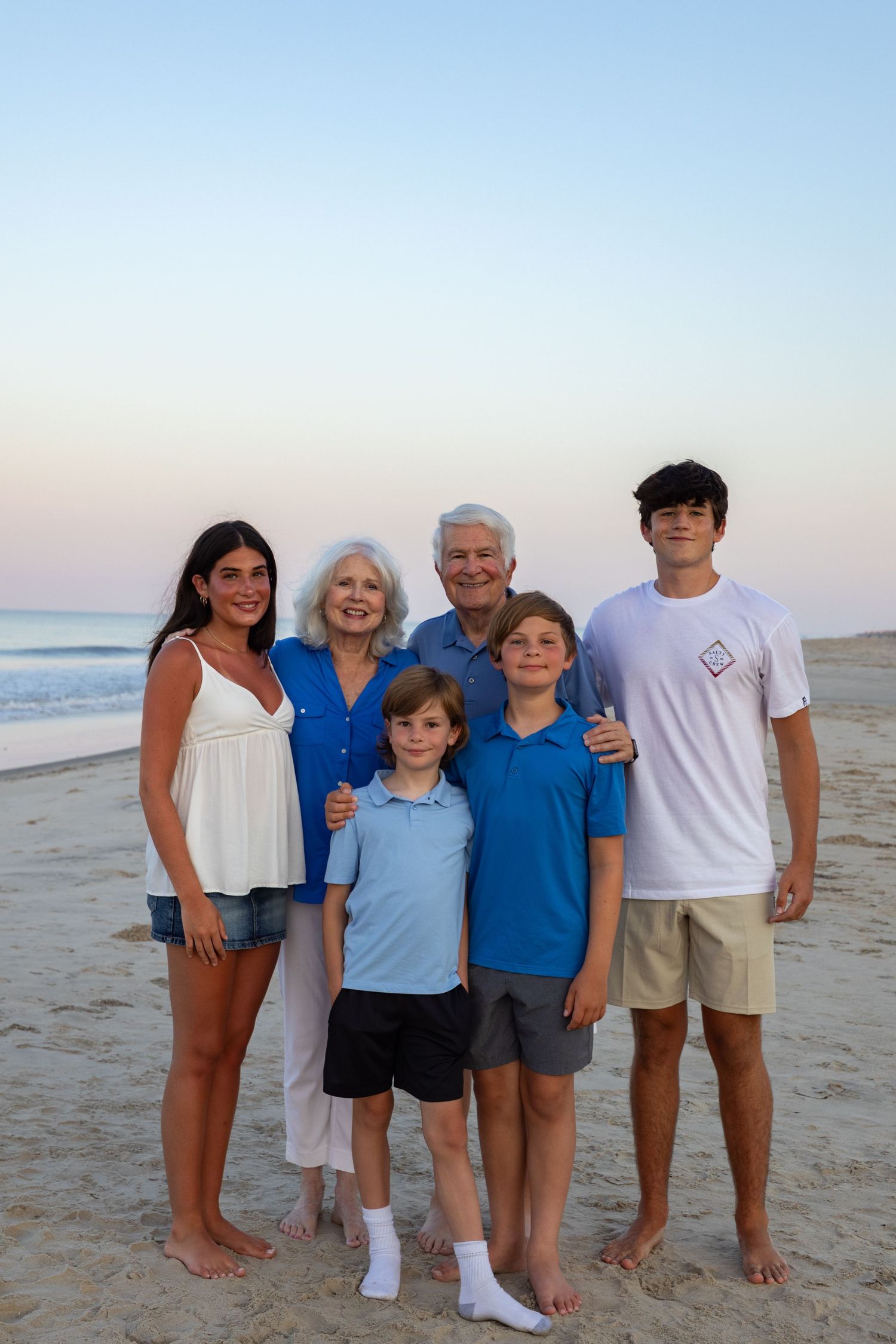 A multi-generational family poses together on the beach at sunset in Outer Banks, North Carolina.