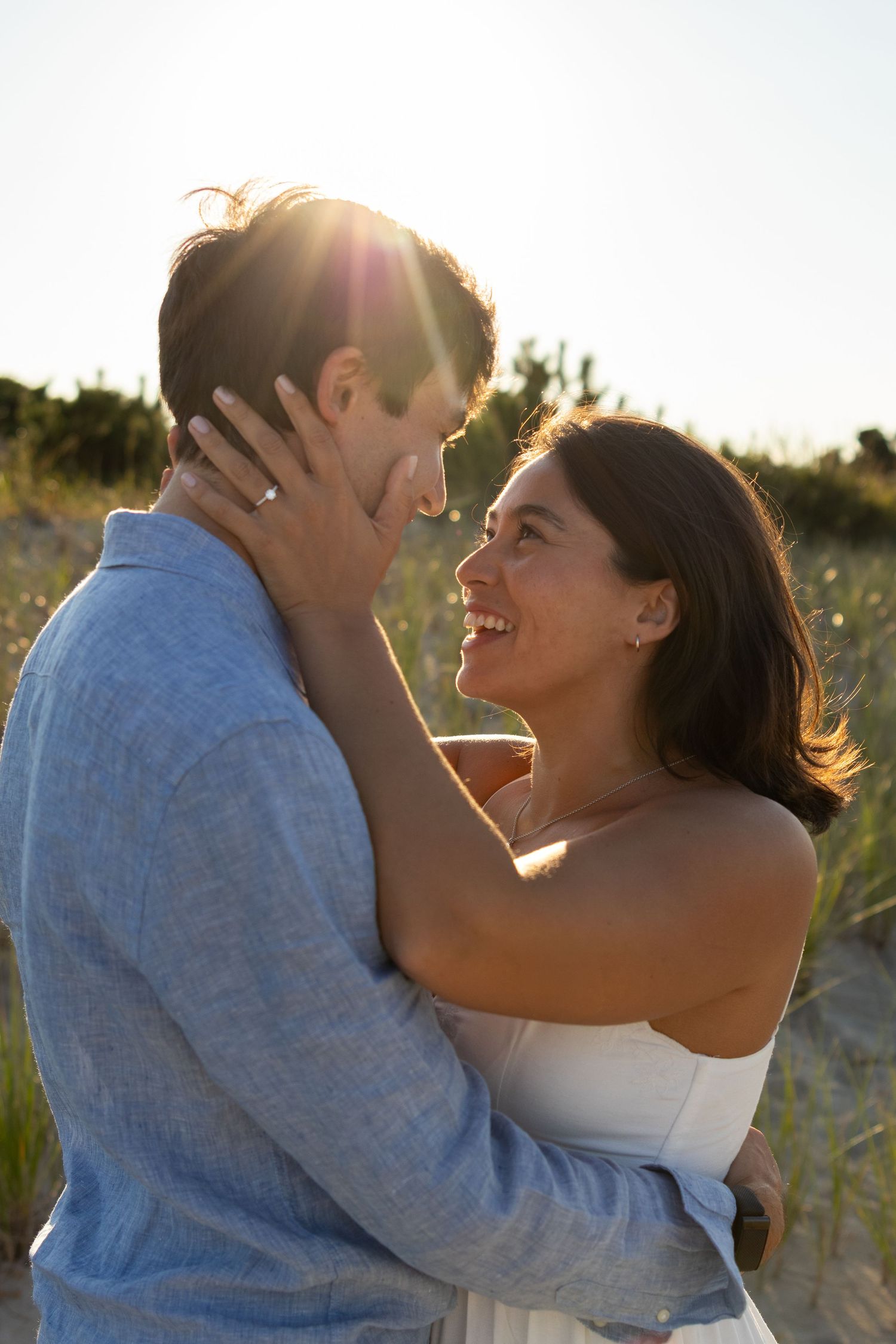 Couple shares intimate moment during beach engagement photoshoot at sunset in Lewes Beach, Delaware.