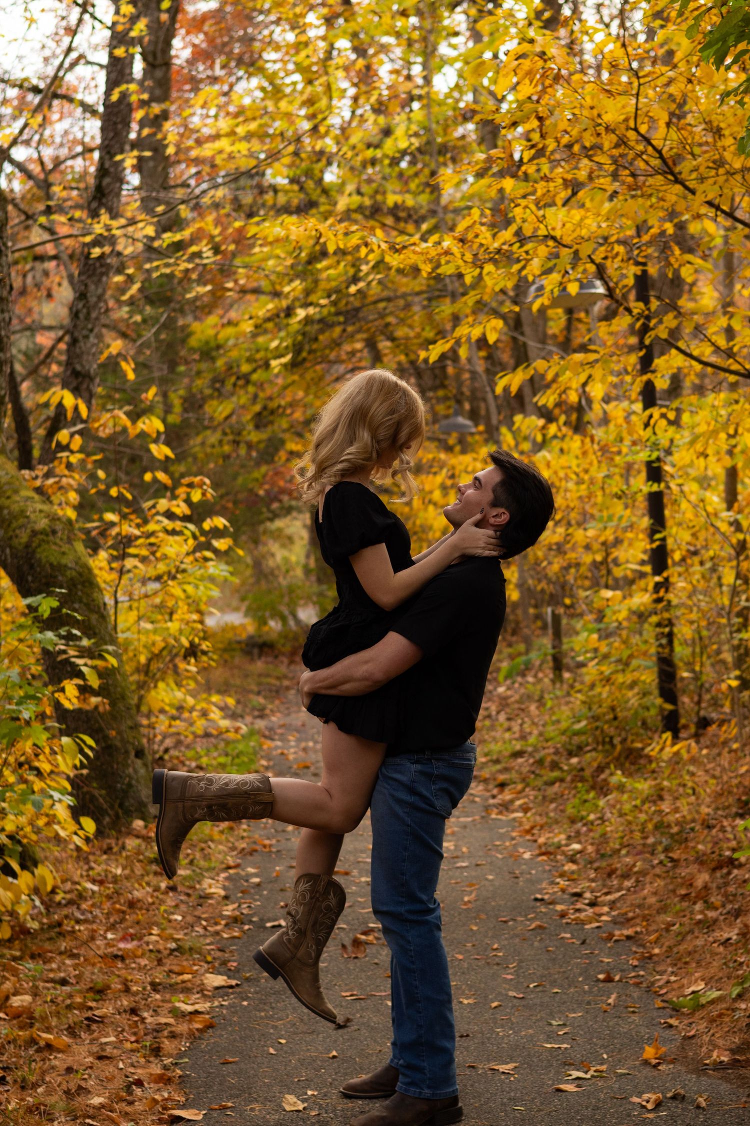 Romantic lift pose on an autumn trail surrounded by golden leaves in Newark, Delaware.