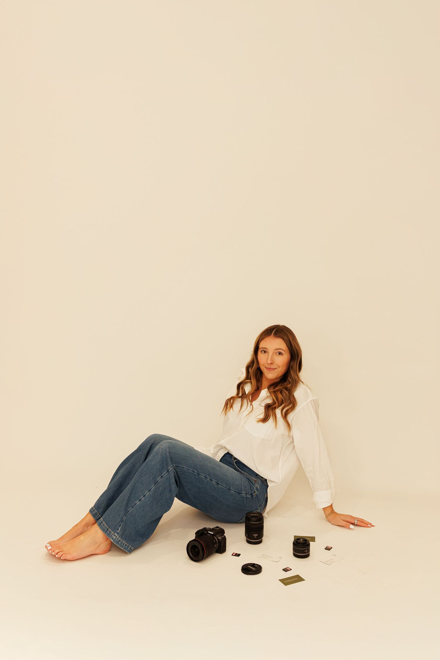 Casual photography setup with camera equipment and relaxed pose against neutral backdrop for Madison Adele Photography.