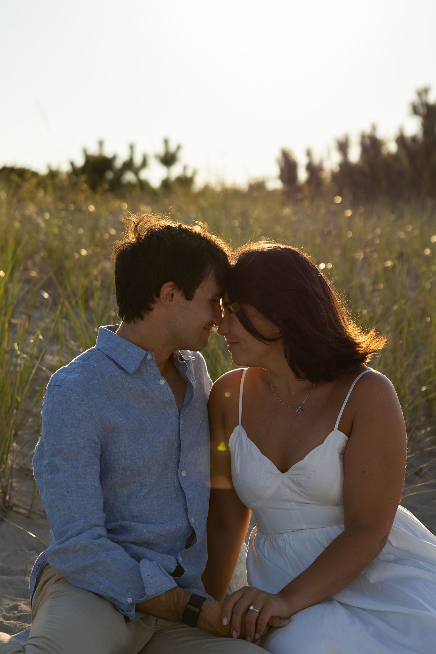 Intimate couple moment captured in field during golden hour for engagement photos in Lewes Beach, Delaware.