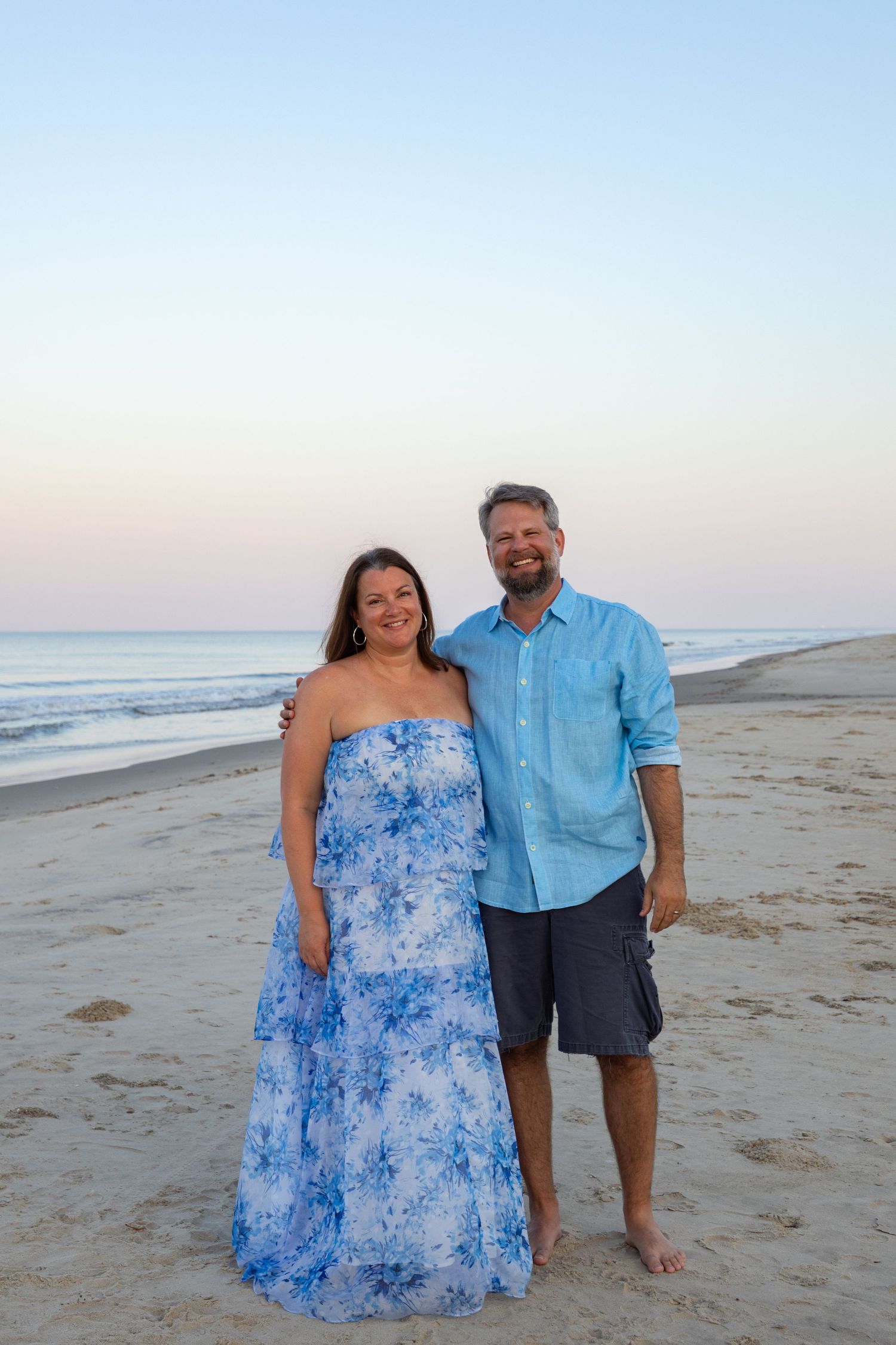 A couple poses together on a serene beach at dusk in Outer Banks, North Carolina.