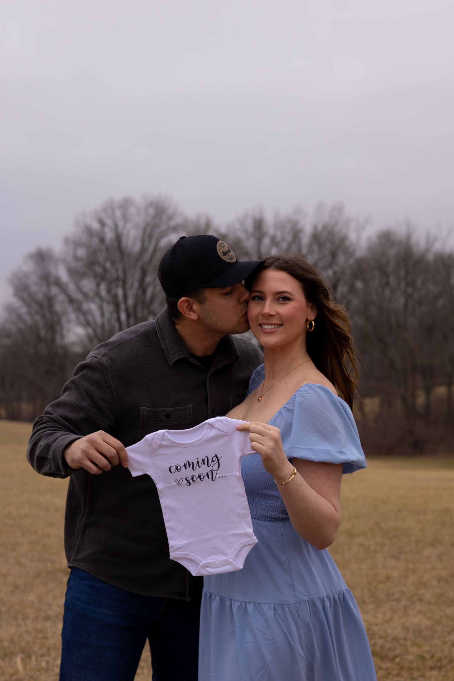 A couple shares a tender moment while holding a baby onesie in a field in Elkton, Maryland.
