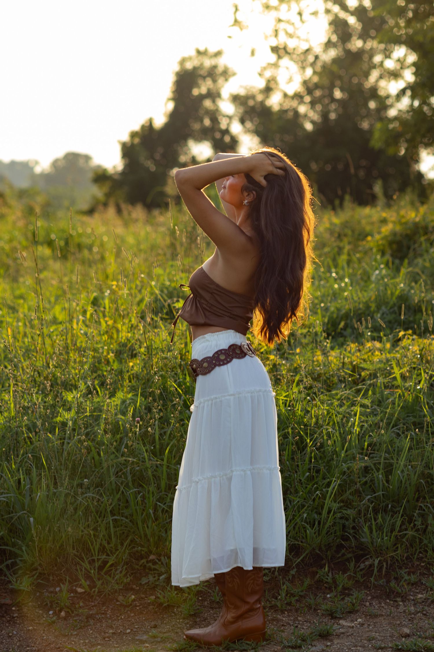 A person in a white dress poses gracefully in a sunlit meadow at golden hour in Wilmington, Delaware.