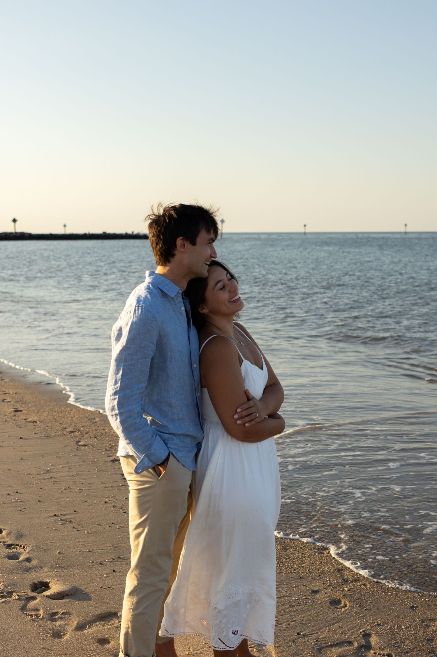 Romantic beach portrait of couple embracing by the ocean at golden hour for engagement photos in Lewes, Delaware.