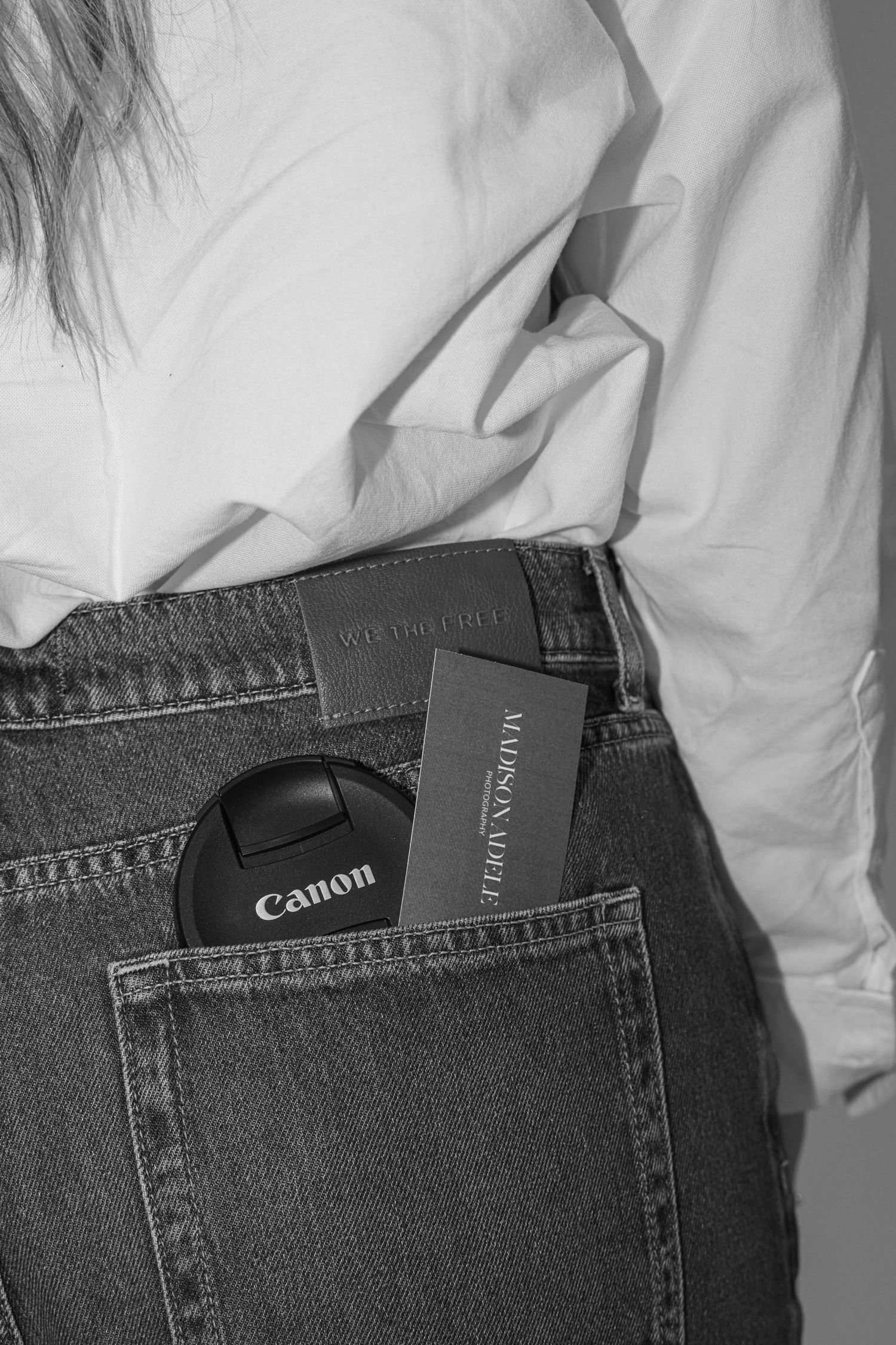 Close-up of Canon camera and memory card in back pocket of blue jeans for Madison Adele Photography.