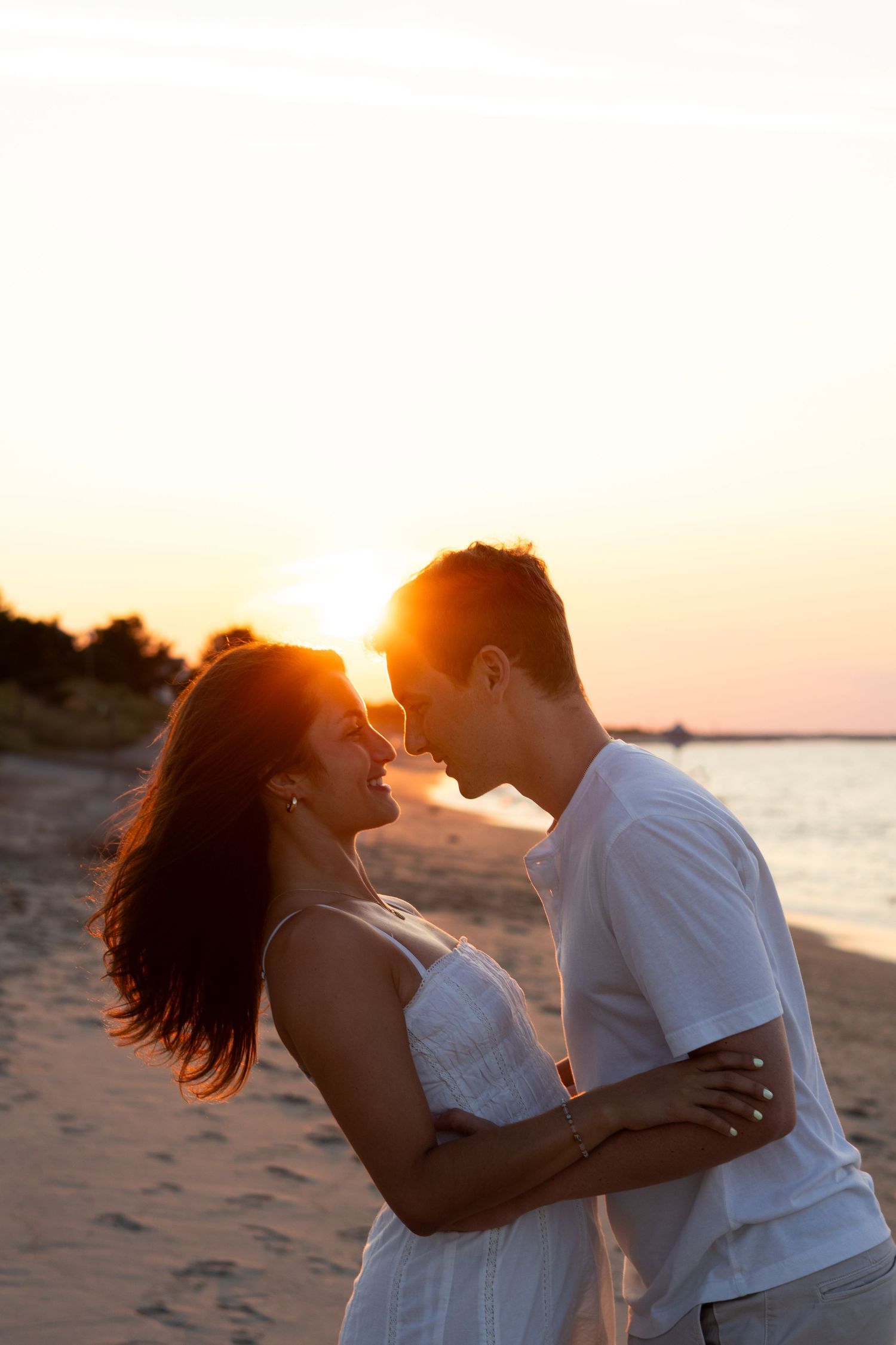 Romantic sunset beach portrait with couple silhouetted against orange sky for engagement photos in Lewes Beach, Delaware.