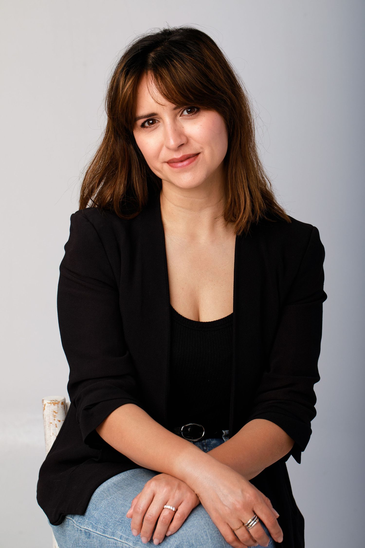 Studio portraits showing casual poses in a black blazer and jeans against a grey backdrop.