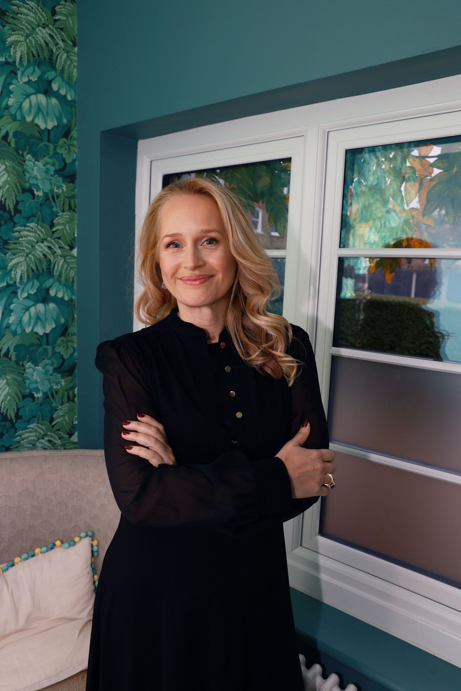 A series of photos shows someone in a black sweater posing playfully against a teal wall with tropical leaf wallpaper.