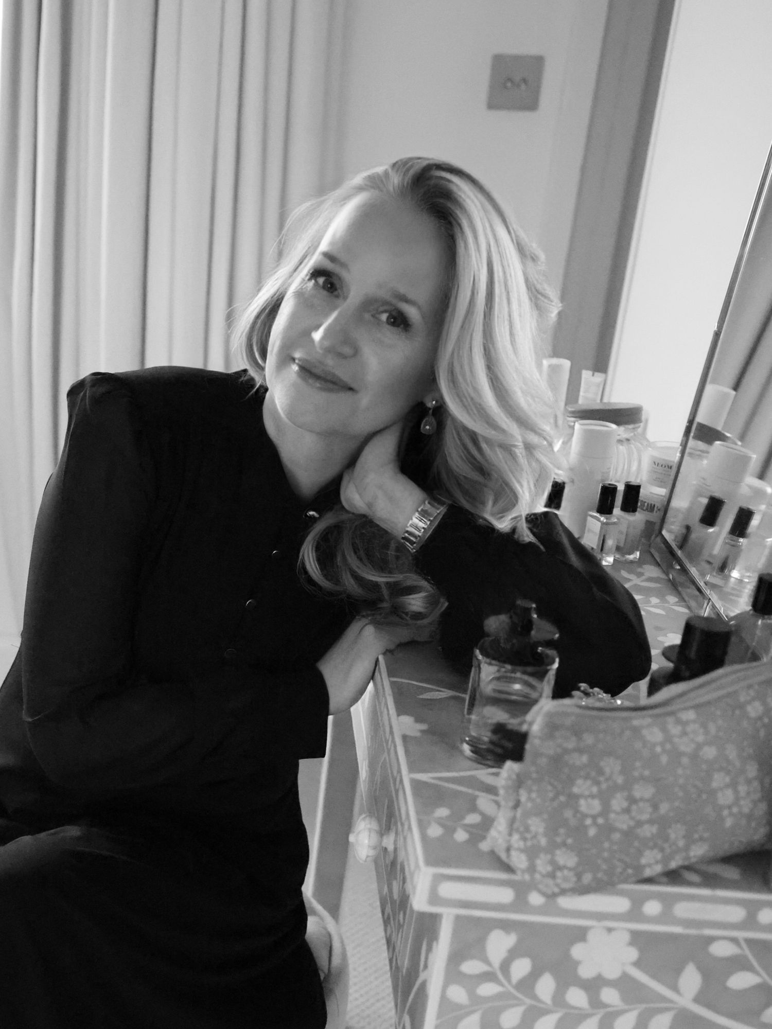 A black and white portrait shows a person in a dark outfit leaning on a table with wrapped presents nearby.