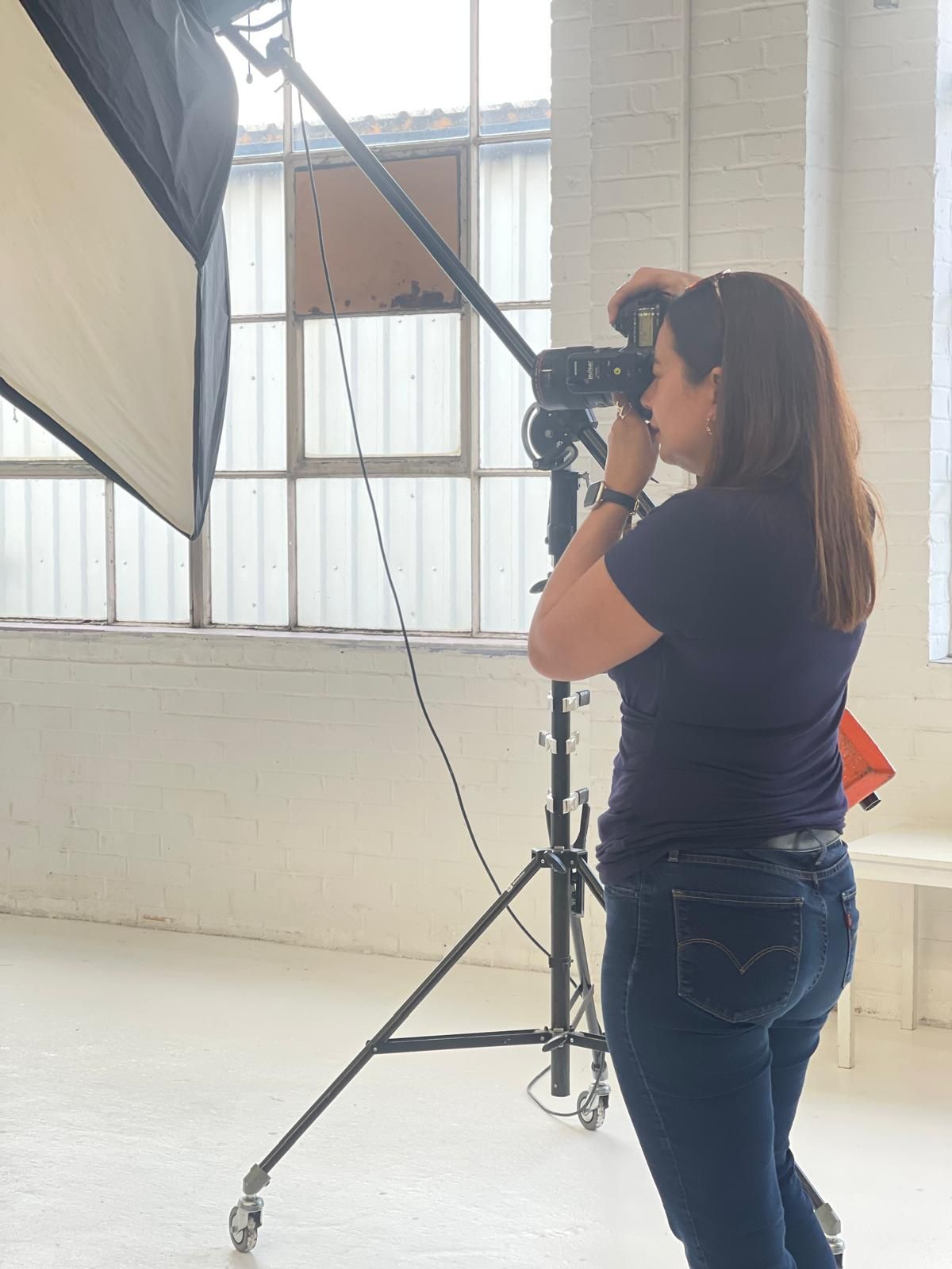 Photographer working with professional lighting equipment in bright studio space.