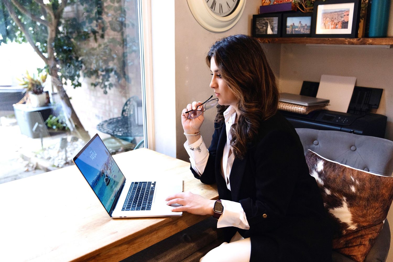 Person sitting at desk working on laptop computer in home office environment with natural lighting.