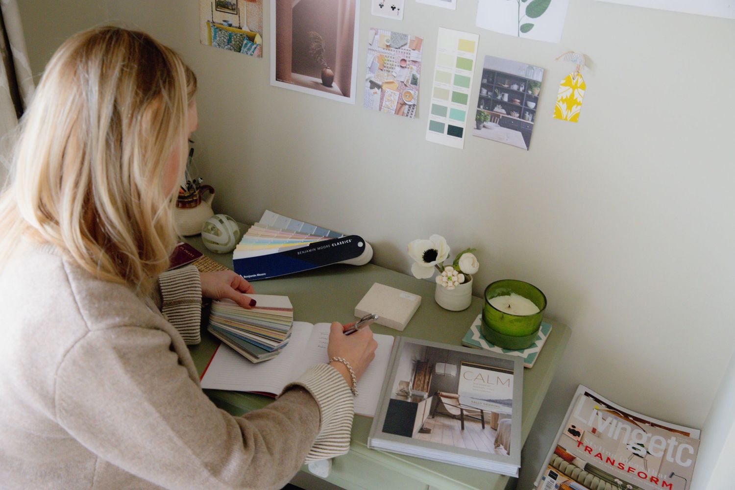 A creative workspace with papers and notes scattered on a desk while someone works at a computer.