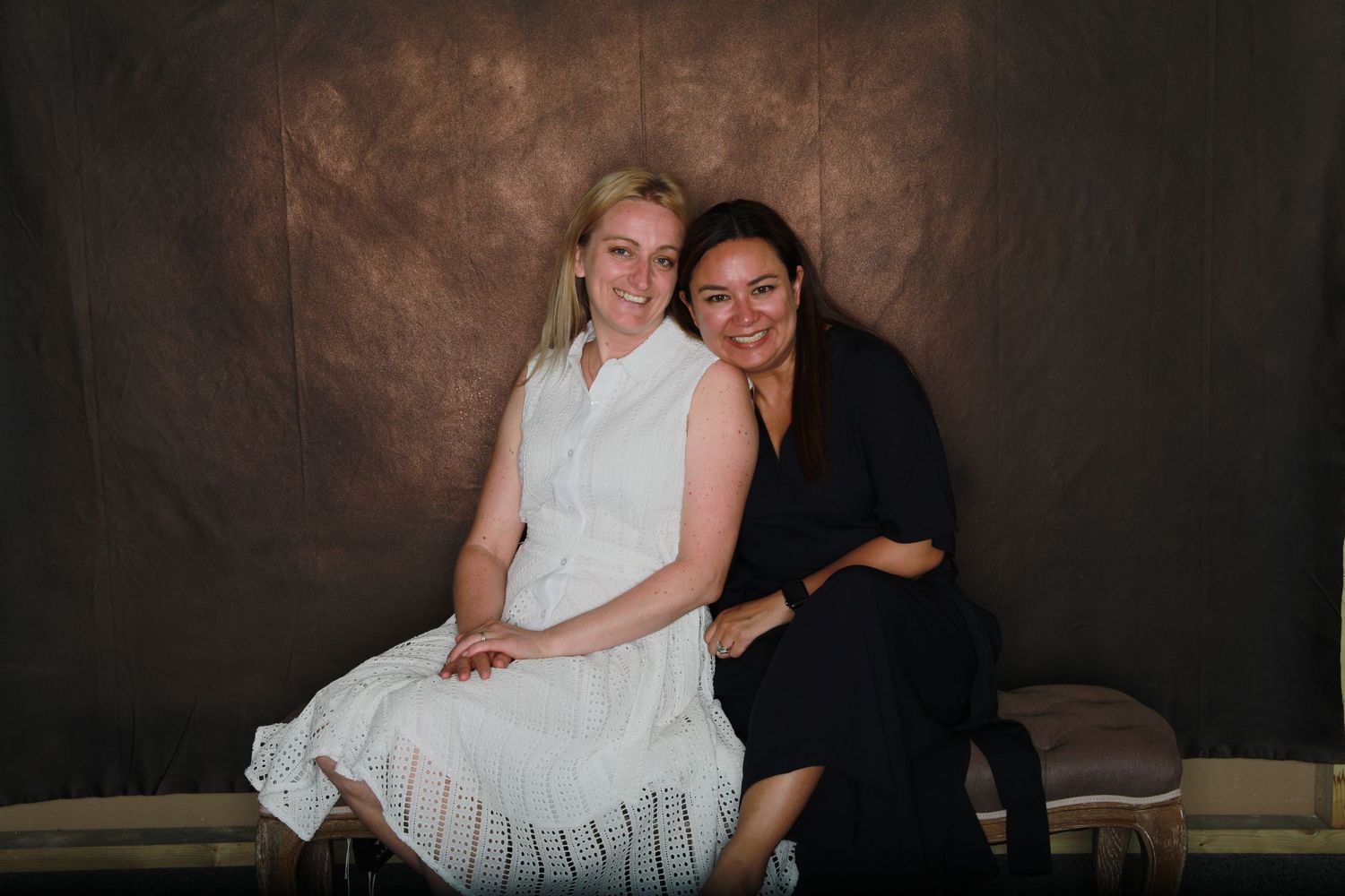 Two people posing together against dark backdrop in formal attire.