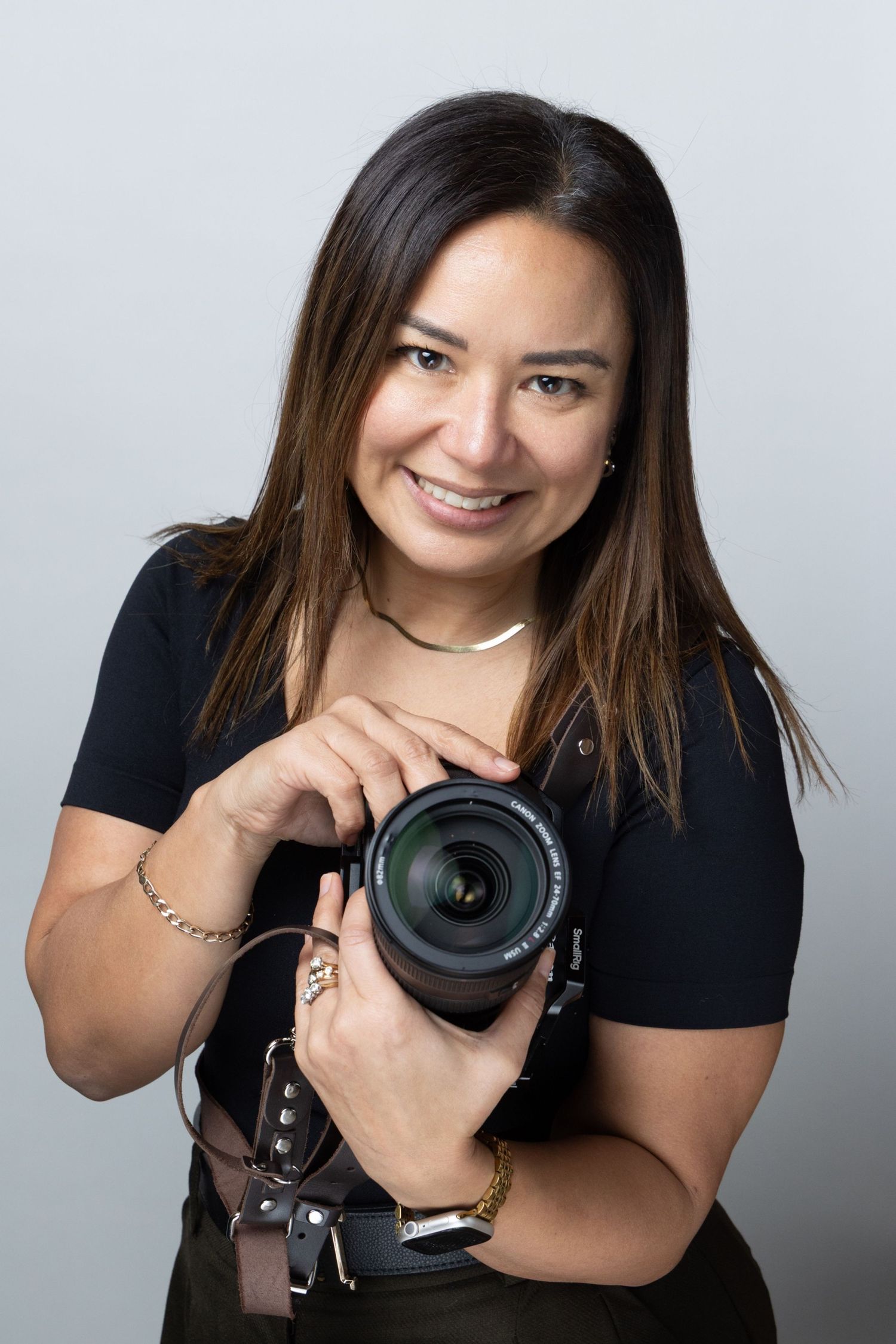 Professional photographer wearing black shirt poses playfully with camera in studio photo series.