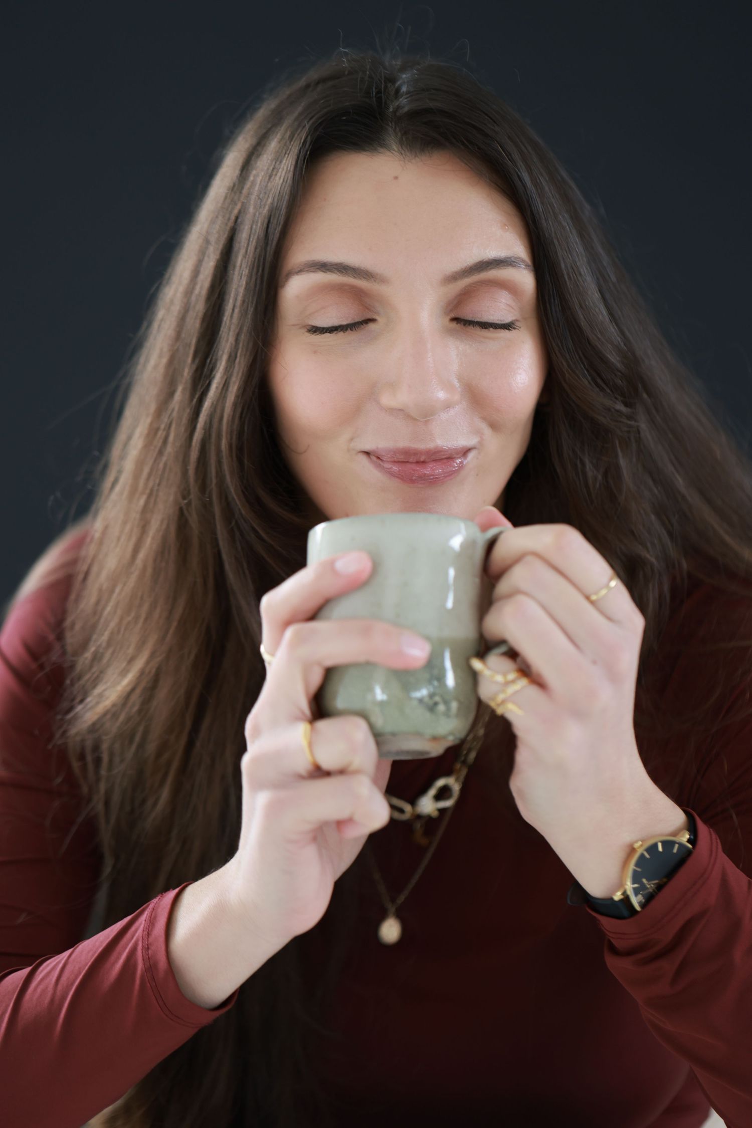 A person in a burgundy sweater enjoys a hot beverage from a small ceramic cup in a sequence of candid photos.