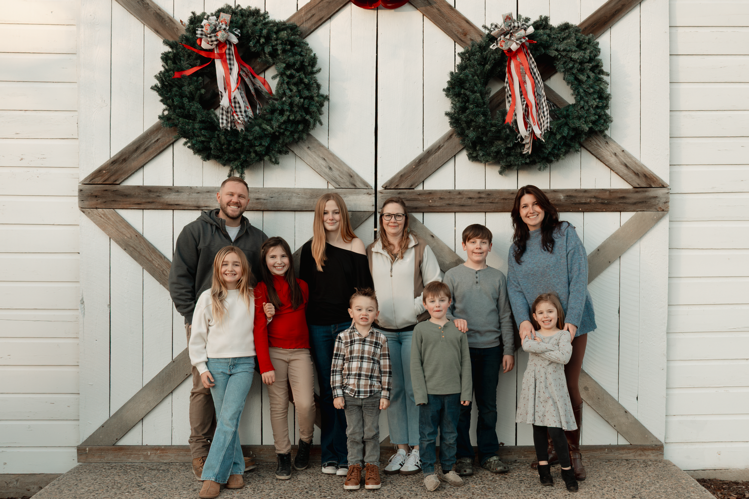 White building exterior with Christmas wreaths and decorative wooden beams at Oak Leaf Acres Farm.
