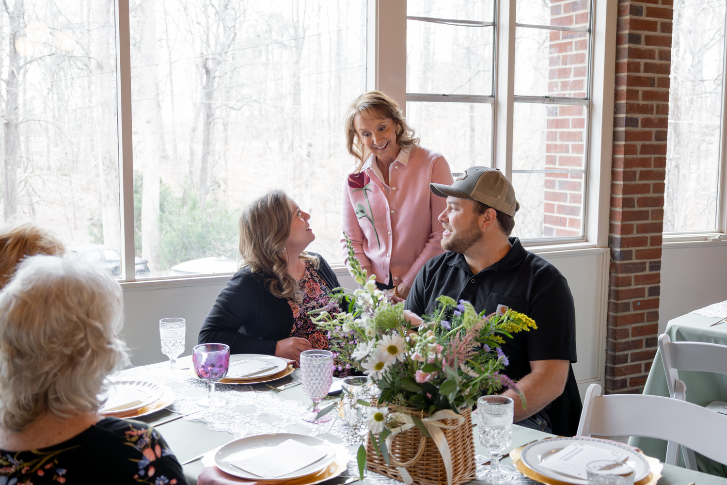 Casual dining scene in bright sunlit room with brick walls and large windows.