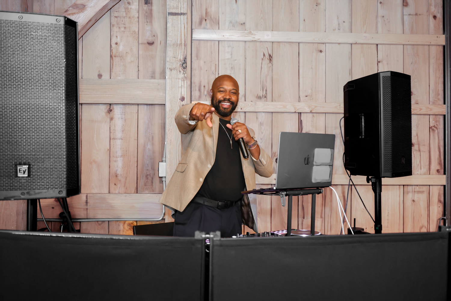 Wide view of a DJ with wood paneling and professional audio gear.