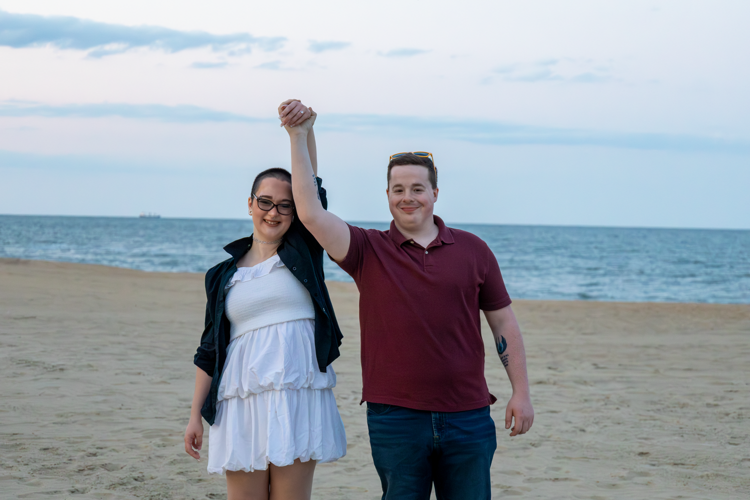 A couple walking together on a sandy Virginia Beach with ocean waves in the background.
