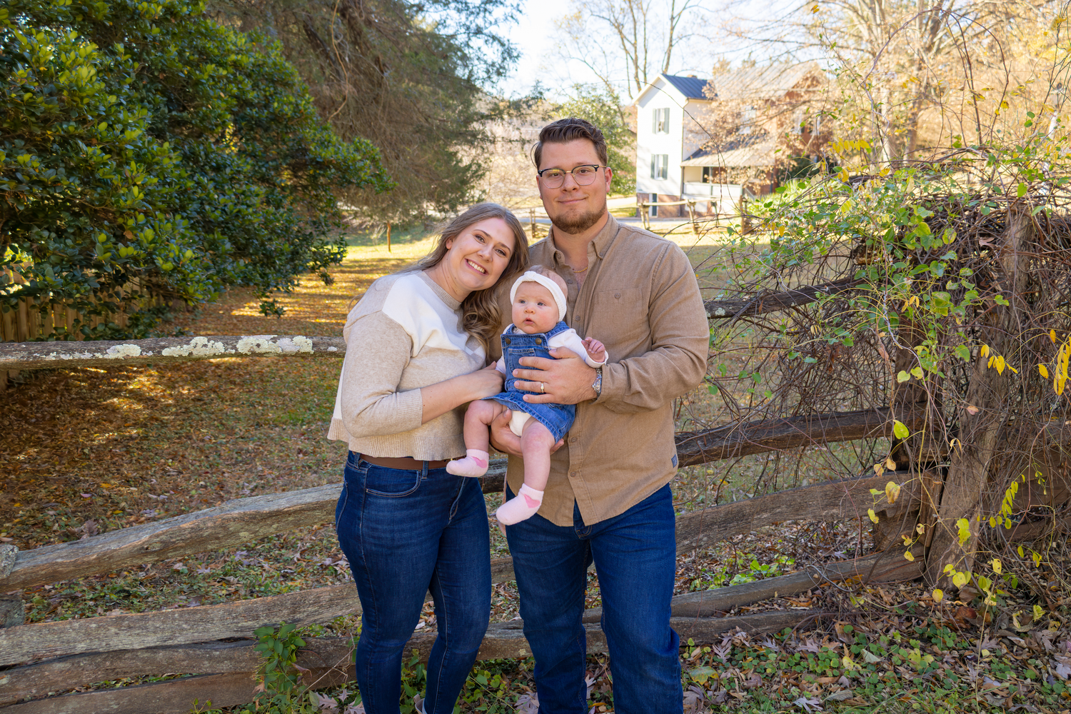 Family photos taken on rustic wooden fence path during autumn season at Old Salem.