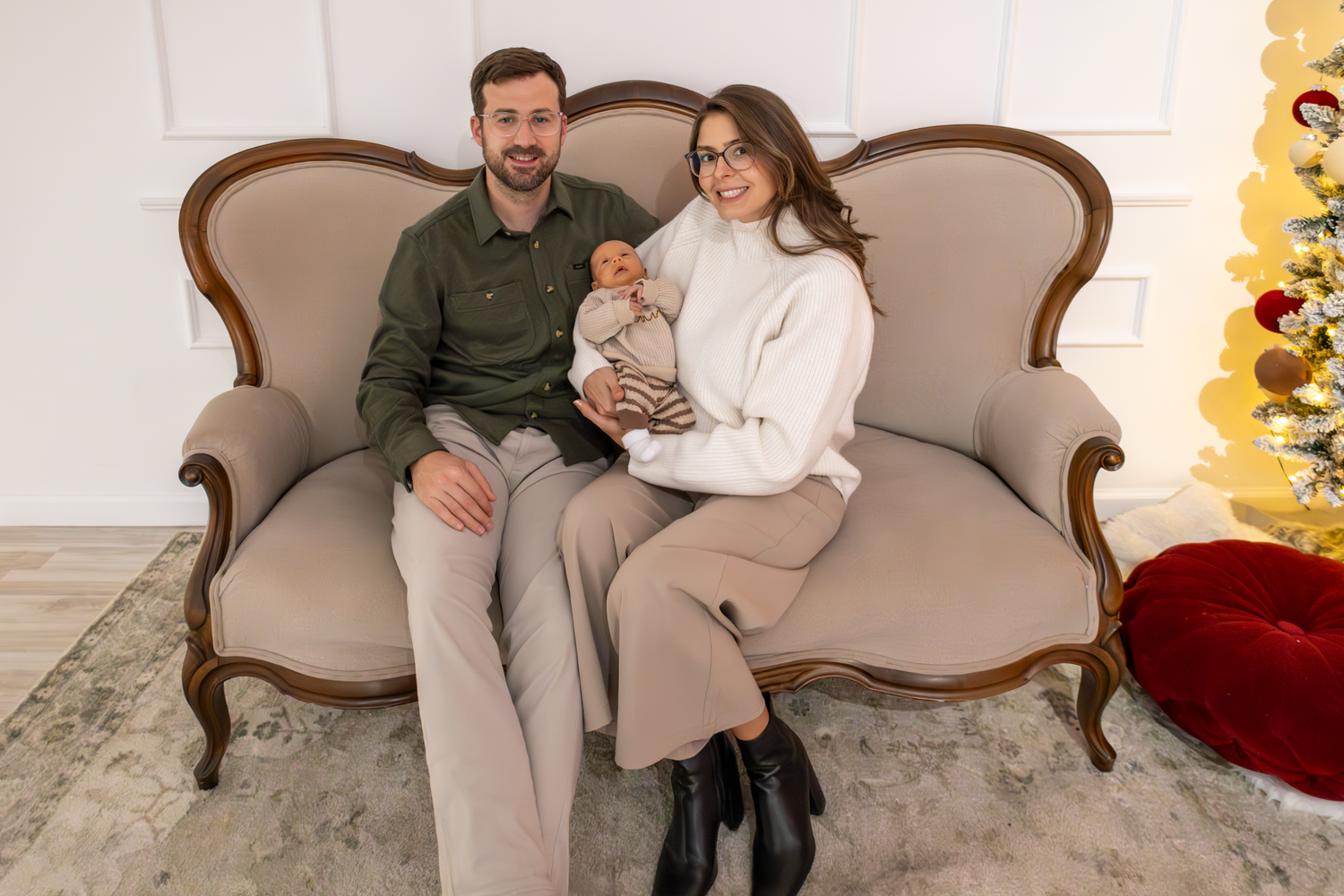 Cozy family portraits on vintage sofa with holiday decorations in background at The GingerBirdie Studio.