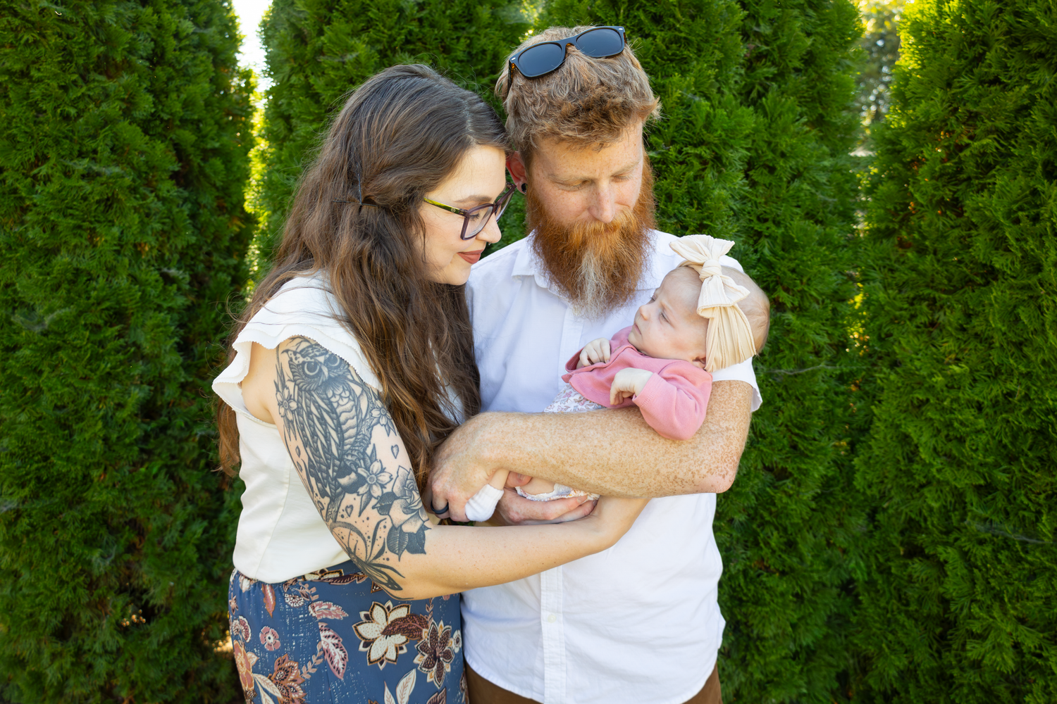 Family sharing tender moments together against lush green hedge backdrop.