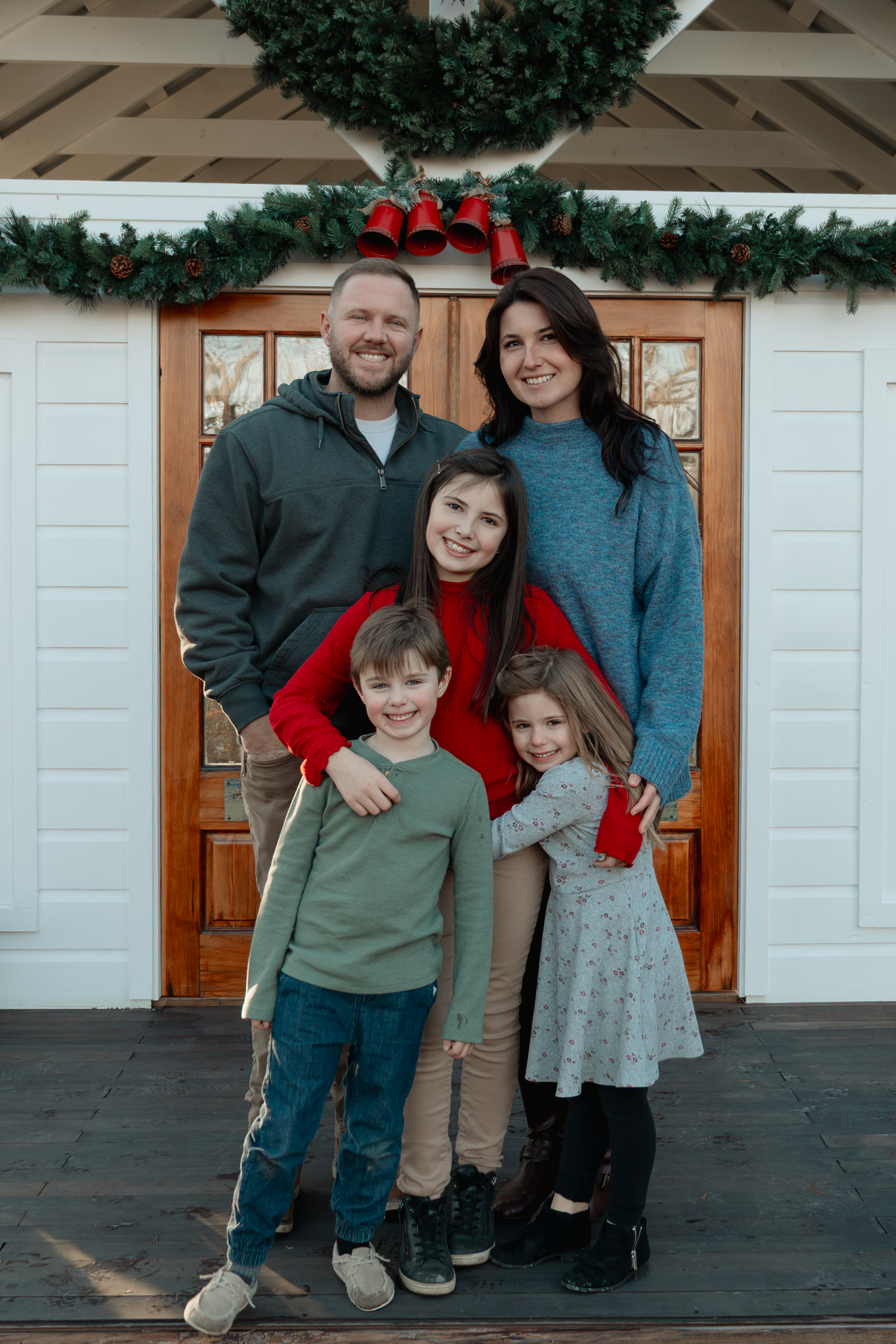 Holiday portrait in front of white building with wooden doors and Christmas decorations at Oak Leaf Acres Farm.