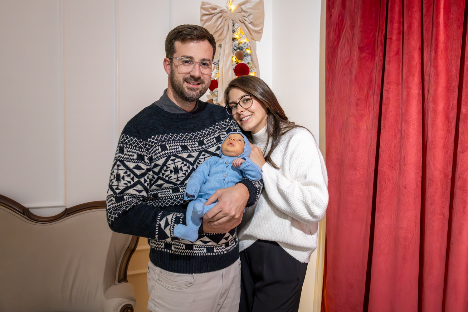 Holiday portraits in front of red curtain backdrop with festive decorations at the GingerBirdie Studio.