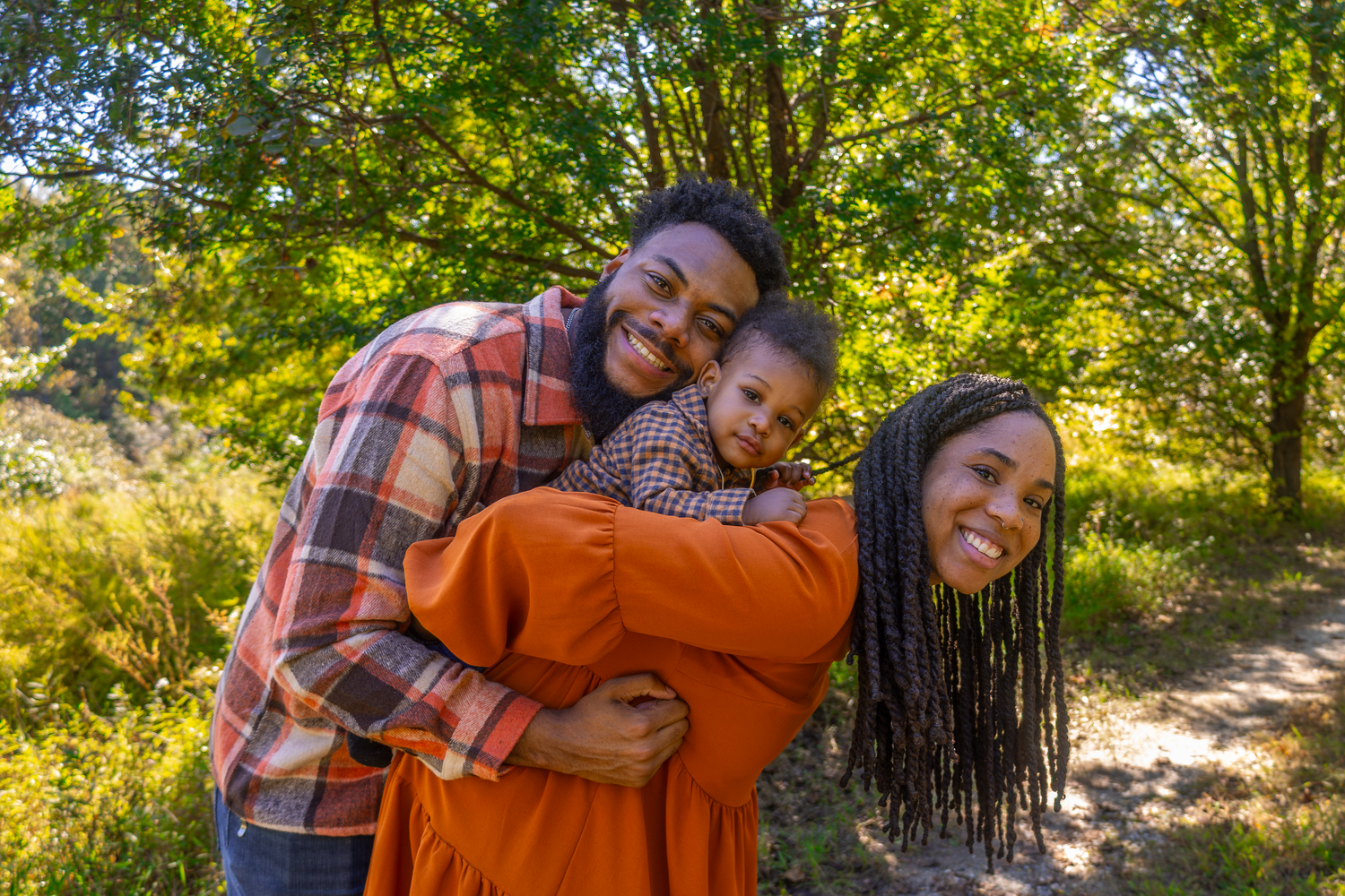 Couple sharing intimate moments under vibrant fall trees in a park setting.