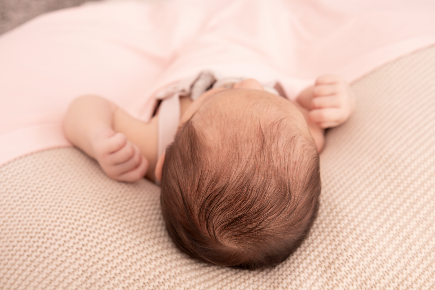 Close-up shots of an infant sleeping on textured beige fabric.