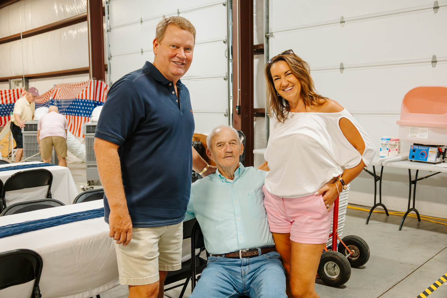 Group of people gathered in a casual indoor setting with white garage doors in the background.