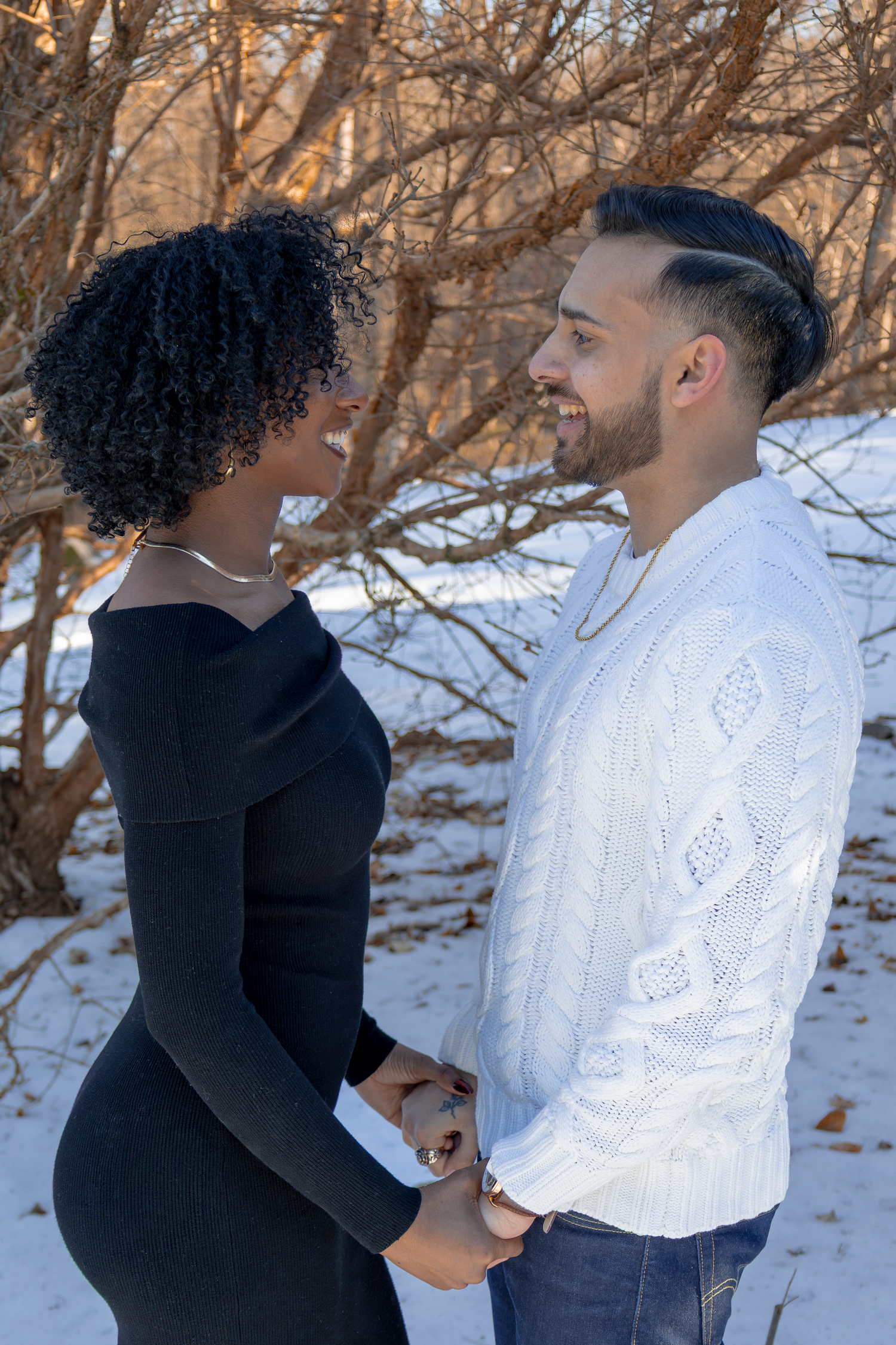 Couple holding hands in winter scene with snow-covered trees in background.