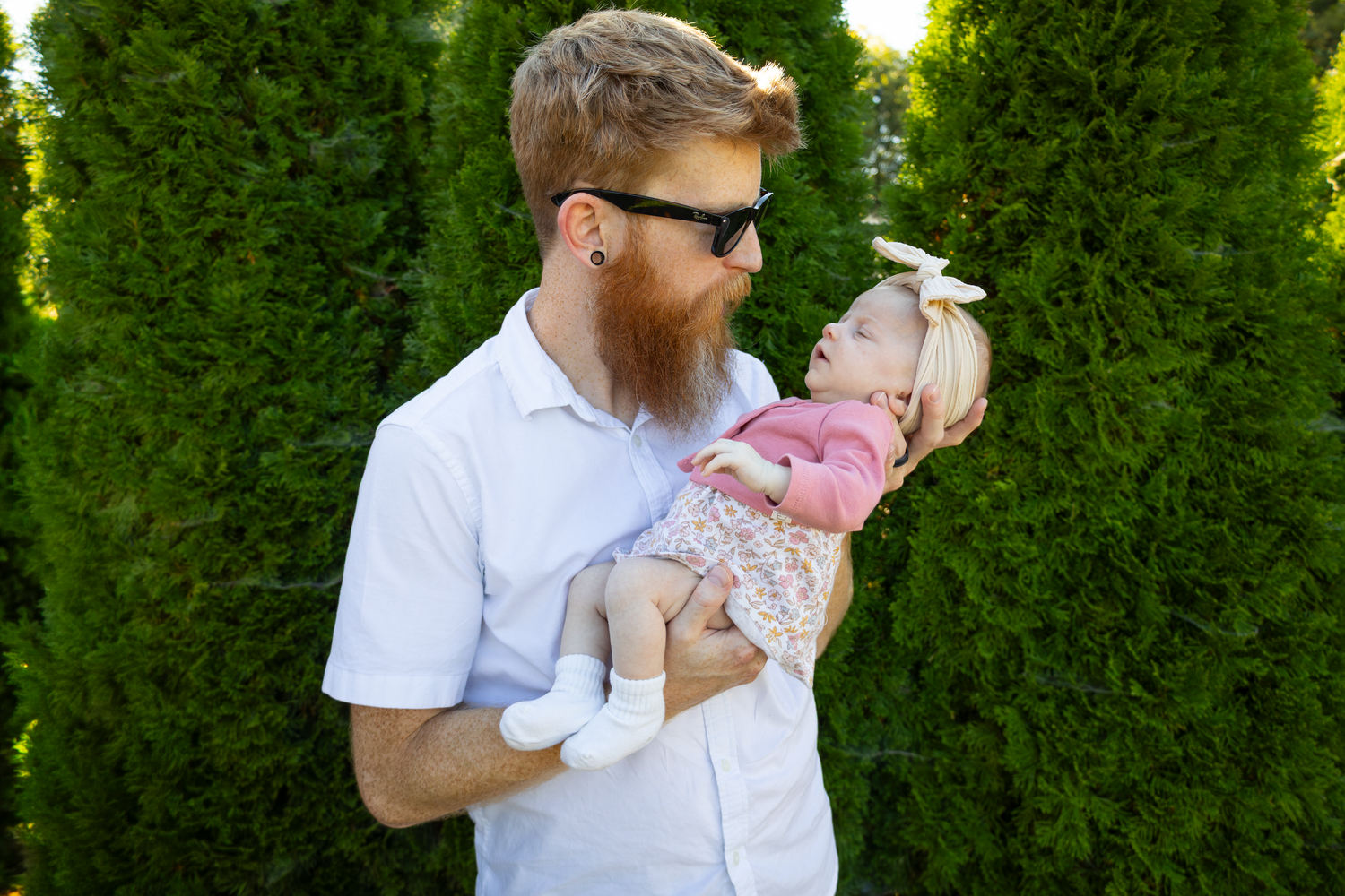 Sweet family interactions captured outdoors with green foliage background.