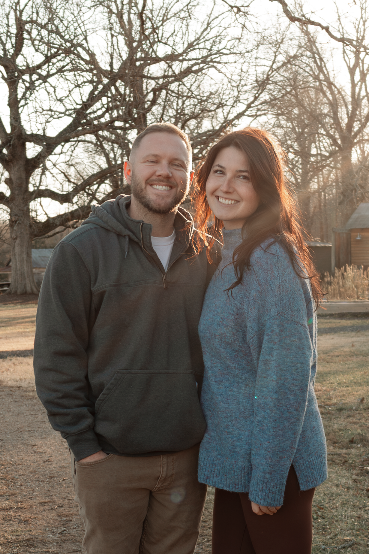 A couple poses together outdoors during golden hour at Oak Leaf Acres Farm.