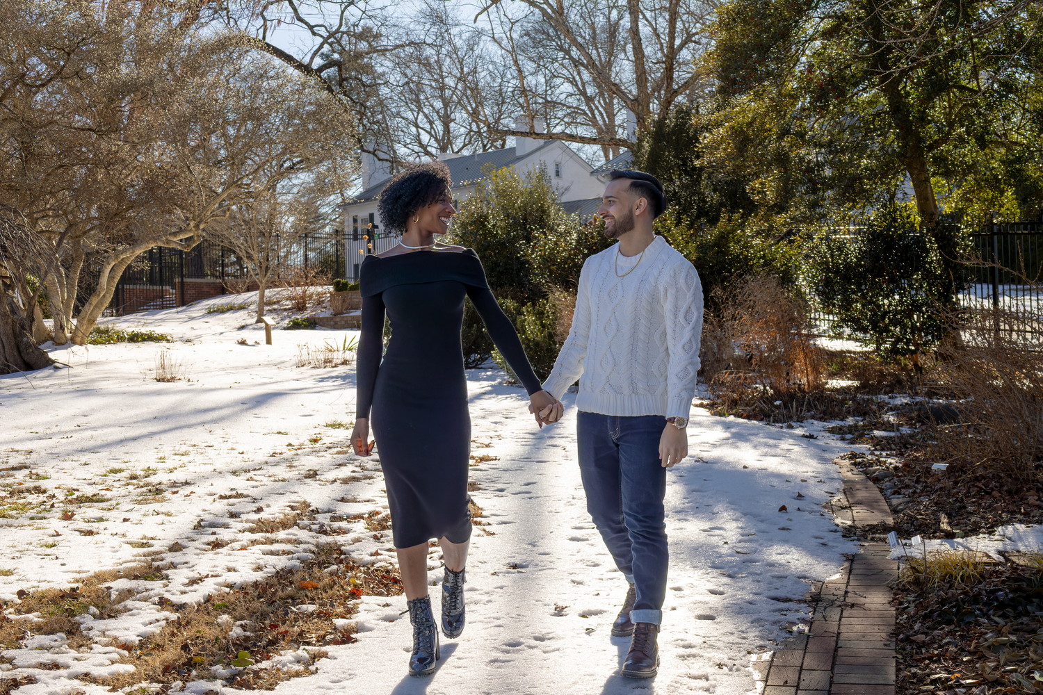 Couple walking together on snowy path surrounded by winter trees.
