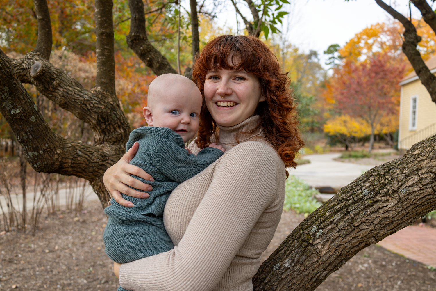 Family enjoying autumn day together under large tree with fall colors at Tanger Family Bicentennial Garden.