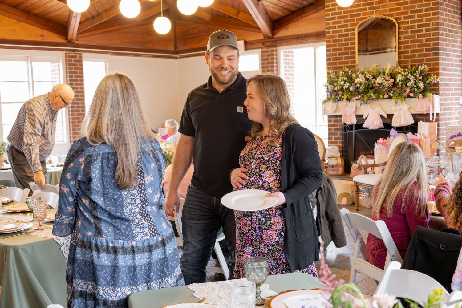 Guests mingle and chat during a festive indoor gathering with exposed brick walls and decorative lighting.
