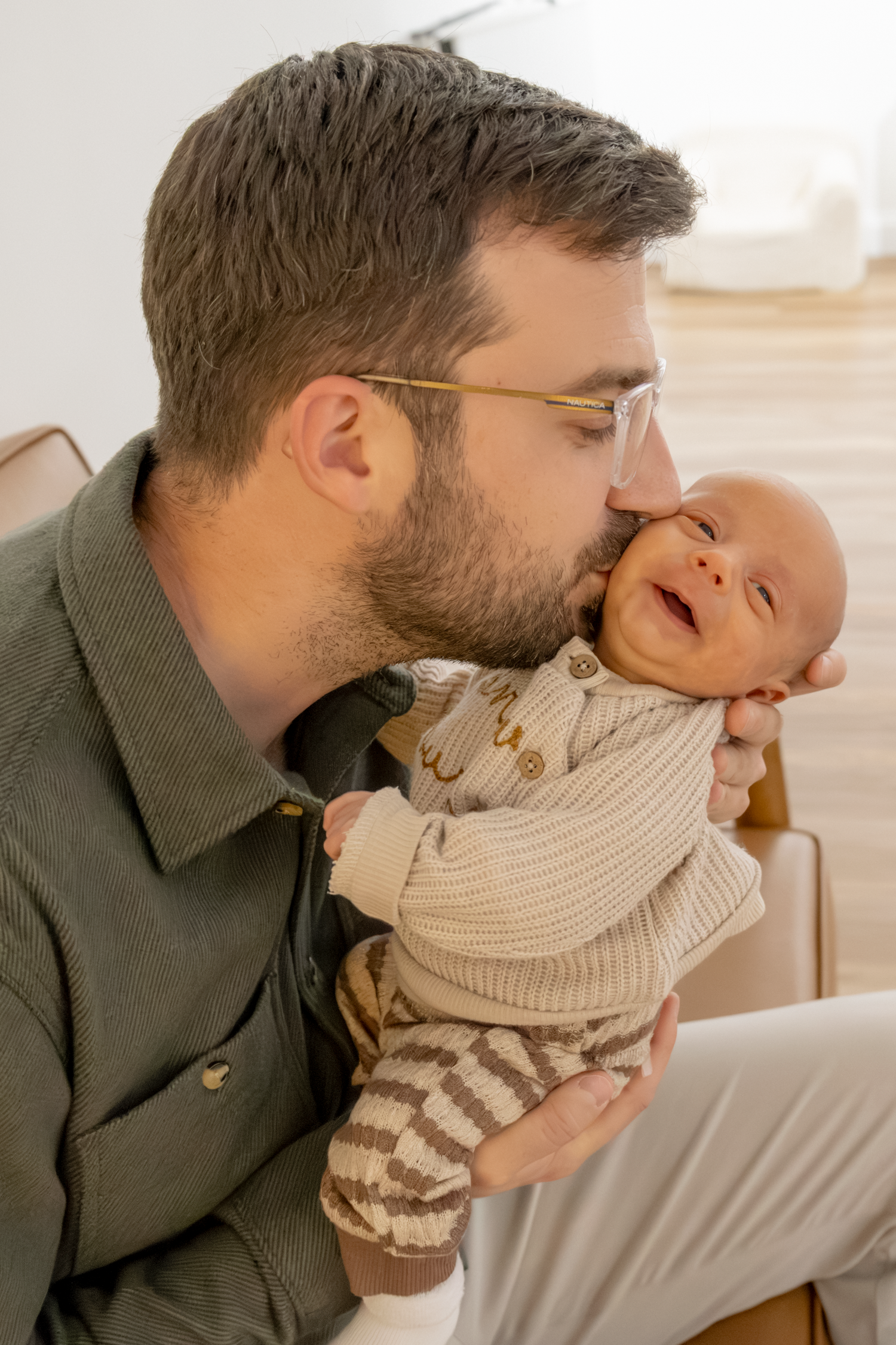 Tender family moment showing affectionate kisses and cuddles with a baby in a cream knit sweater at The GingerBirdie Studio.