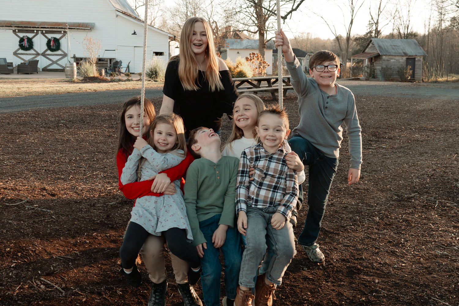 Group posing together outdoors in casual clothing on brown ground during autumn at Oak Leaf Acres Farm.