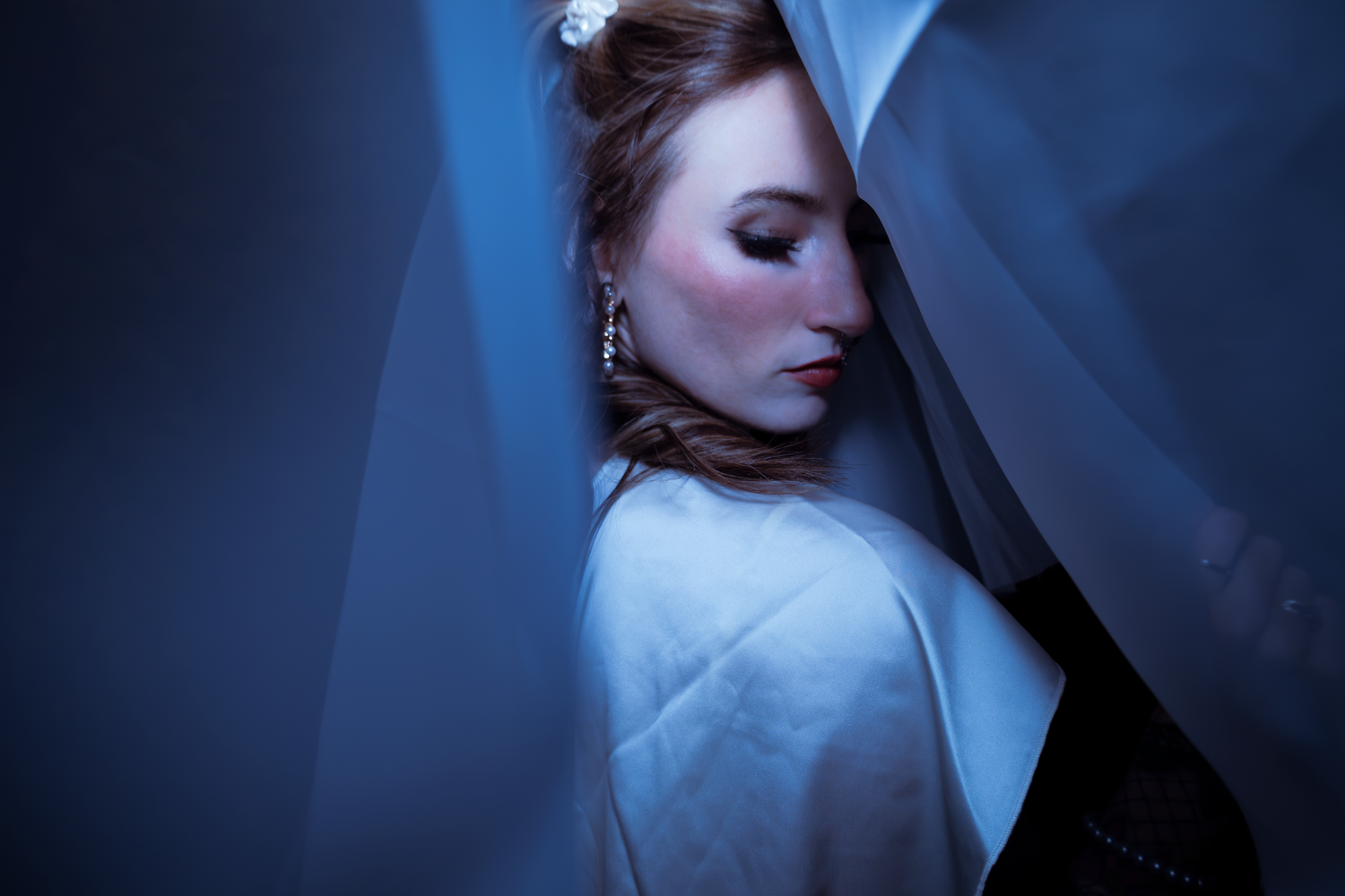 Dramatic fashion photos with blue lighting and flowing white fabric creating ethereal atmosphere.