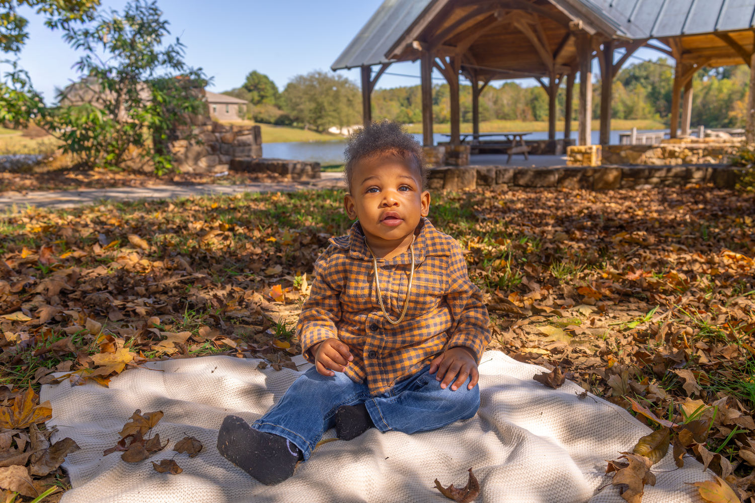 Fall family photos with couple laying in autumn leaves near wooden structure.