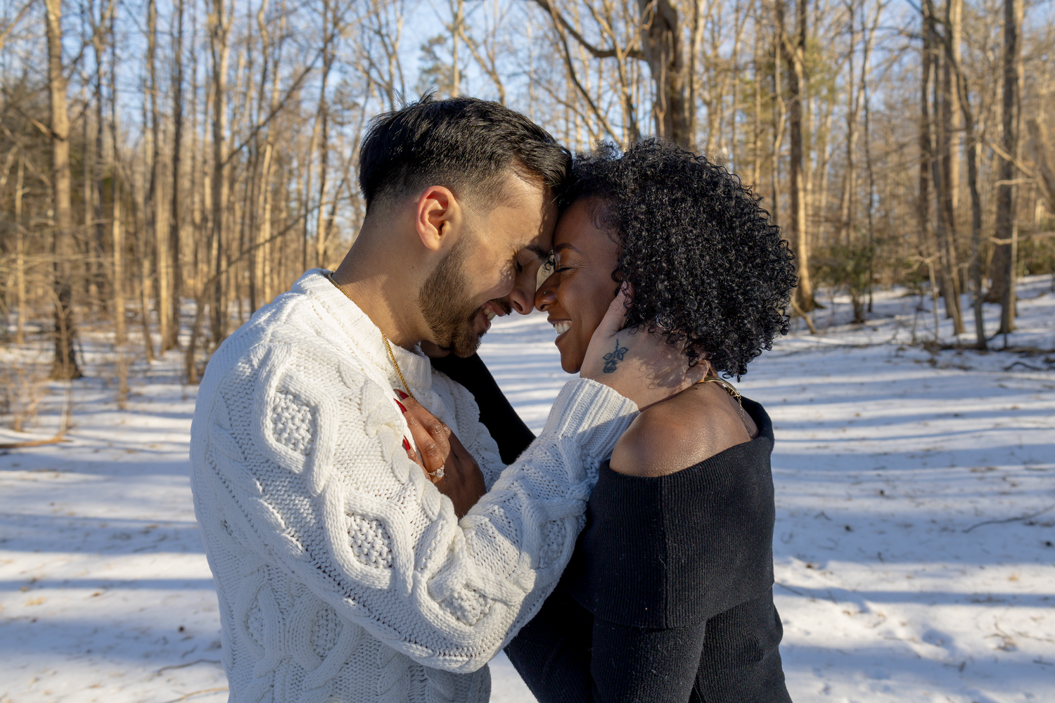 A romantic couple shares an intimate moment in a snowy winter forest setting.