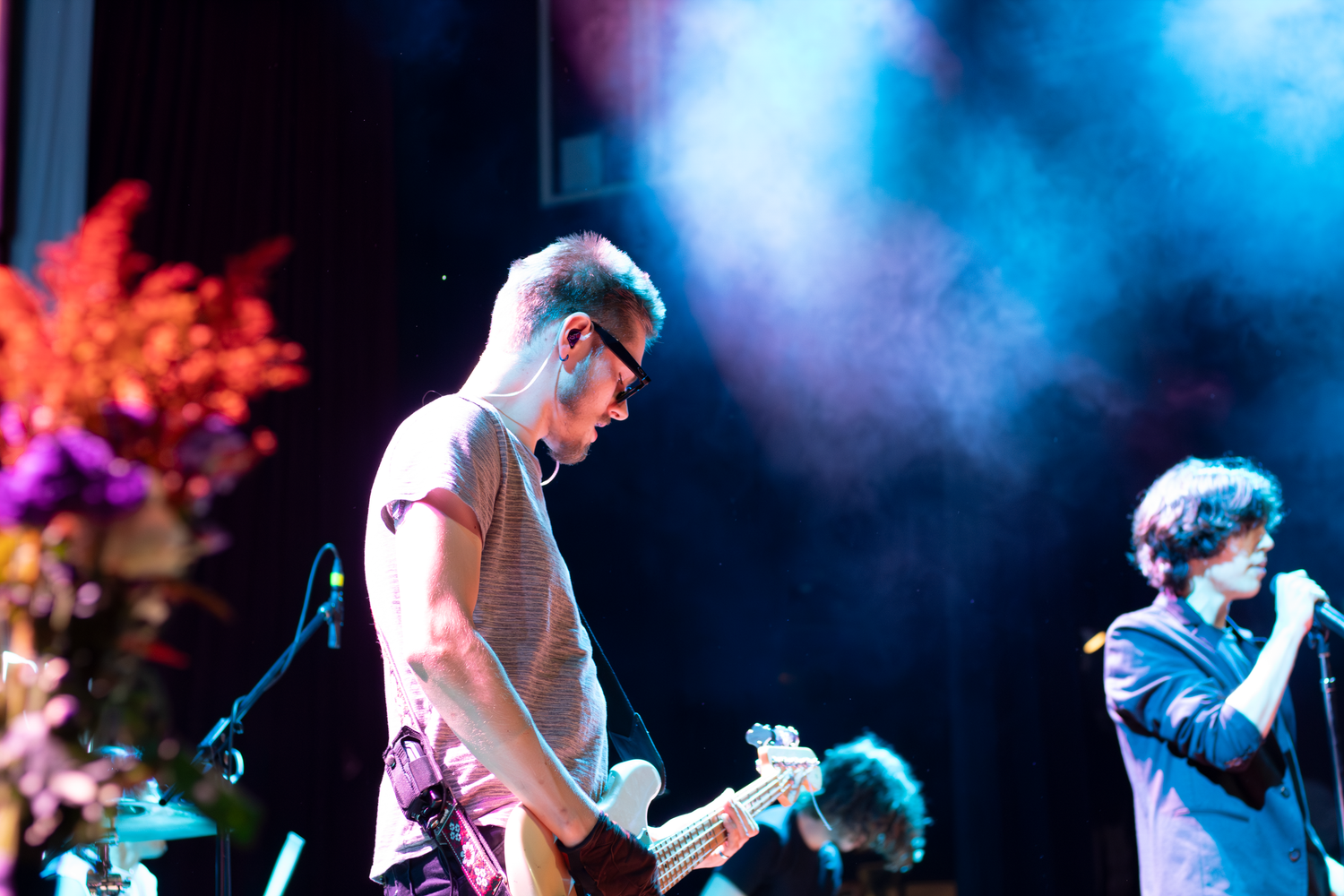 Live music performance on stage with dramatic blue lighting and fog effects.