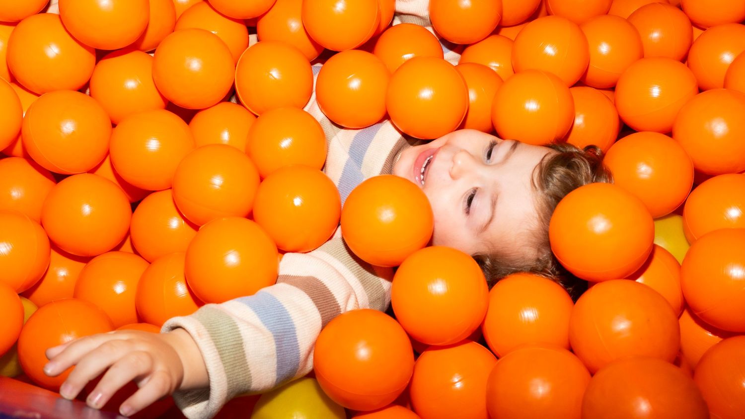 fotografia em festa de aniversário infantil com criança brincando na piscina de bolinhas.