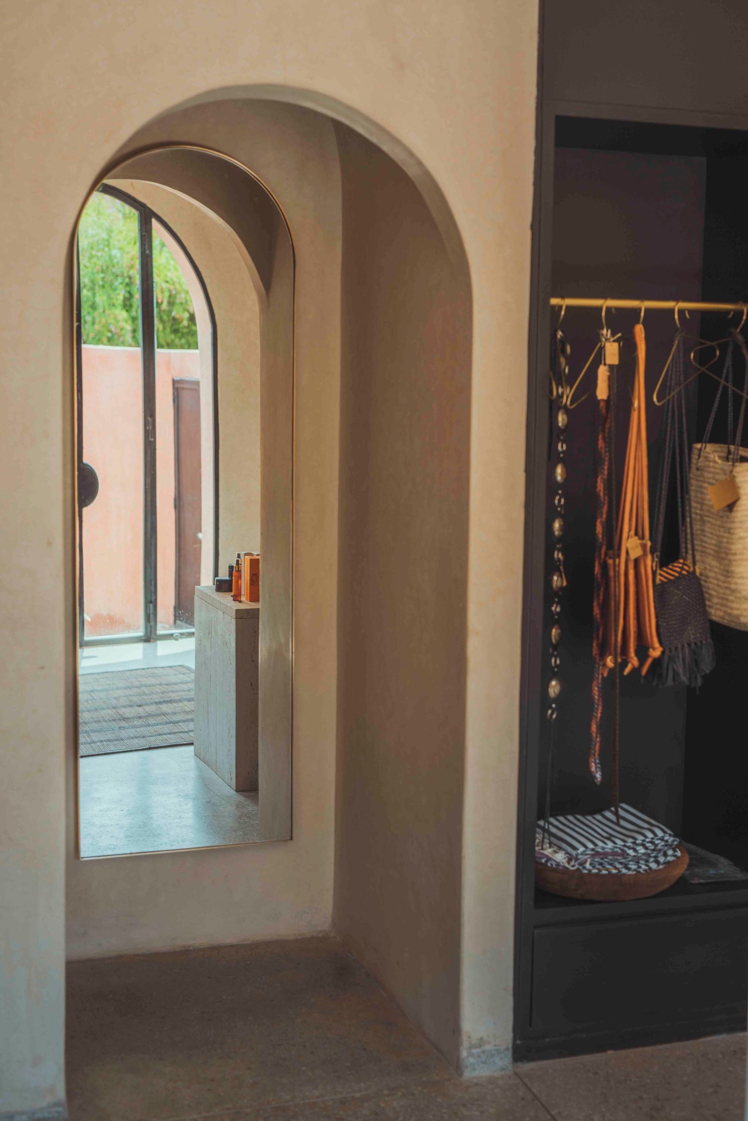 Arched doorway with hanging clothes rack in modern desert-style interior.